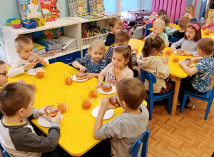 Dzieci jedzą pączki przy stolikach